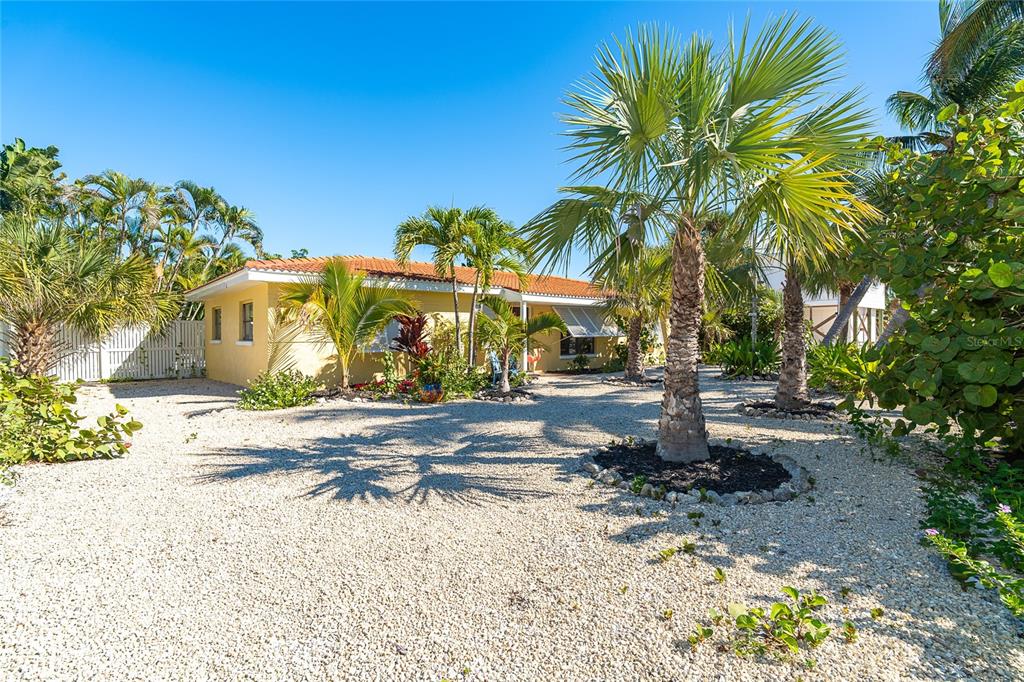 A yellow single-story house with a tiled roof sits on a gravel lot with palms — 90 N GULF BOULEVARD, PLACIDA, FL
