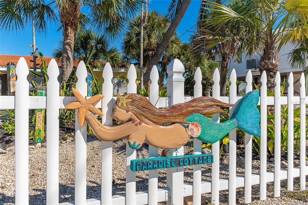 A mermaid-shaped sign labeled Paradise Cottage is mounted on a white picket fence — 90 N GULF BOULEVARD, PLACIDA, FL