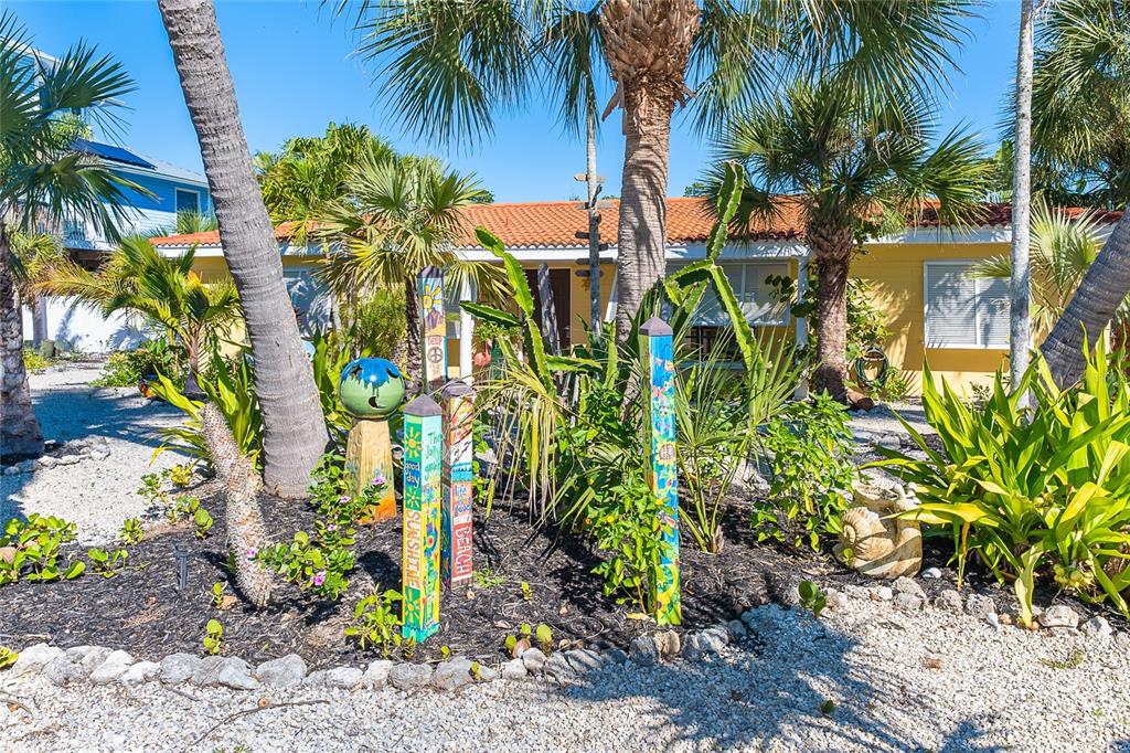 A yellow house with a tile roof is surrounded by palm trees and garden decor — 90 N GULF BOULEVARD, PLACIDA, FL