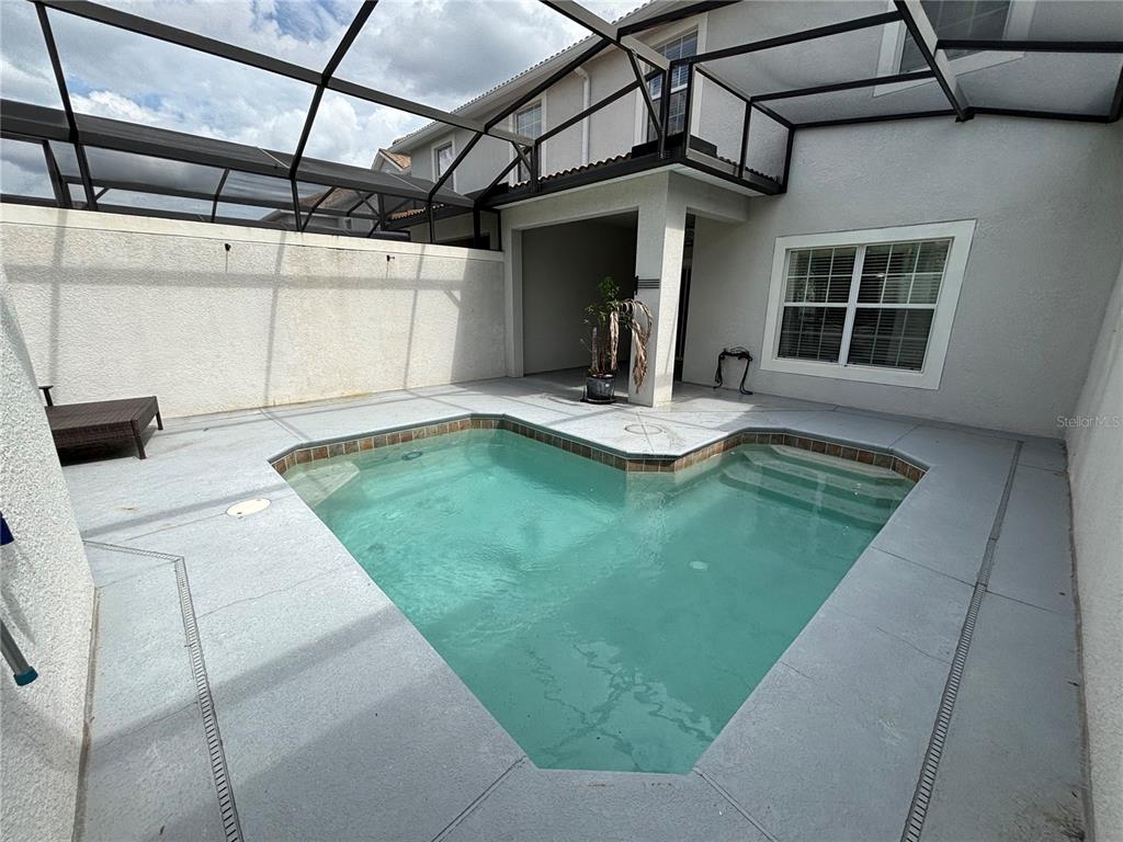 A screened-in patio features a heart-shaped swimming pool and light gray concrete decking — 1591 MOON VALLEY DRIVE, DAVENPORT, FL