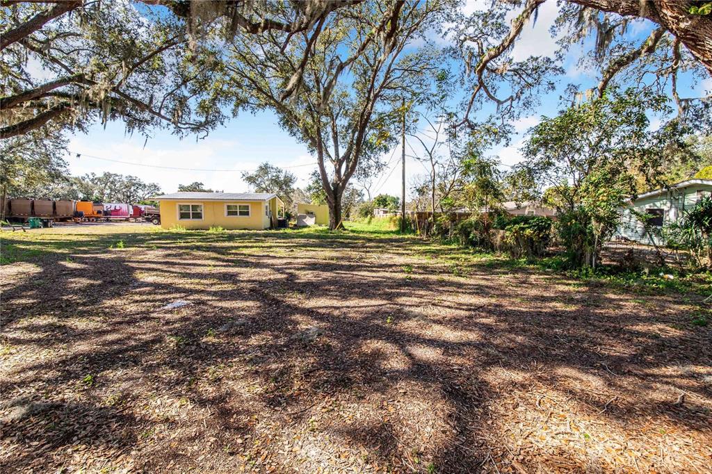 A large, shaded dirt lot features a yellow house in the background under mature trees — FOUSE AVENUE, DUNDEE, FL