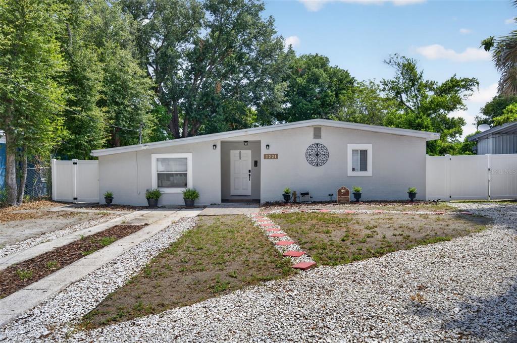 A single-story house with a light gray exterior, white trim, and a gravel front yard — 1221 ELINORE DRIVE, ORLANDO, FL