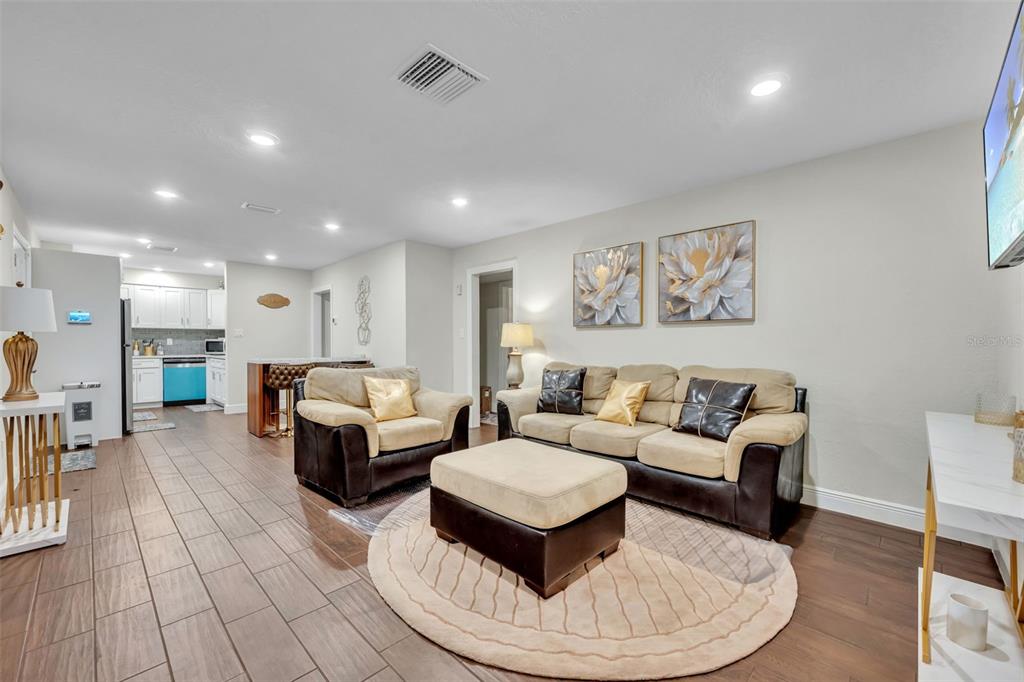 A living room with tile floors, a beige sofa set, and an open kitchen area — 1221 ELINORE DRIVE, ORLANDO, FL