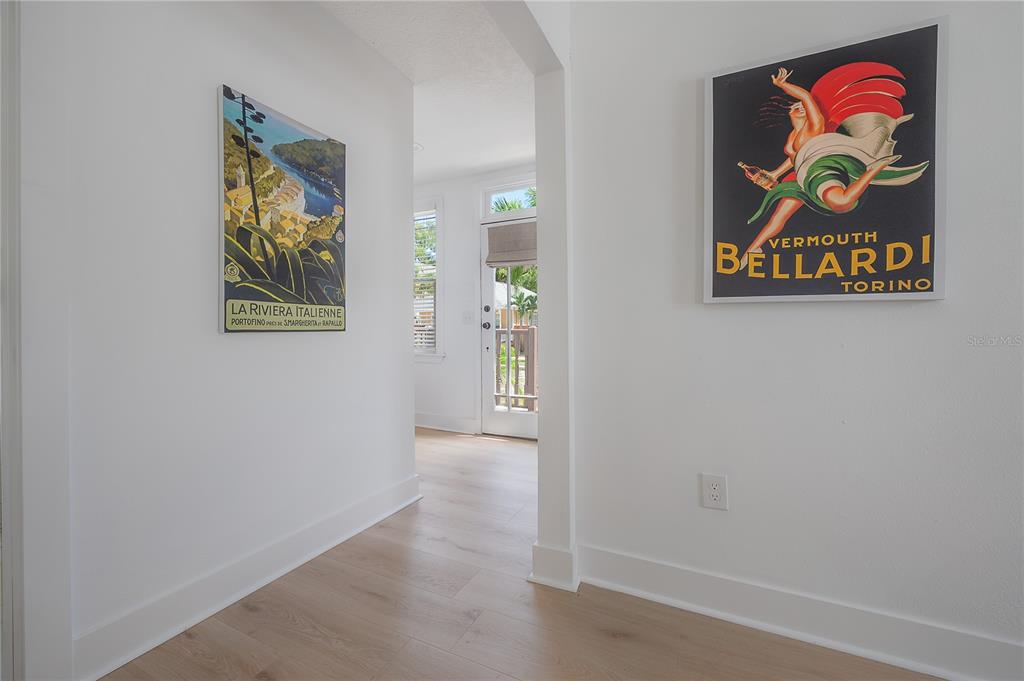 A bright hallway with light wood flooring features two vintage-style posters on white walls — 408 E AMELIA AVENUE, TAMPA, FL