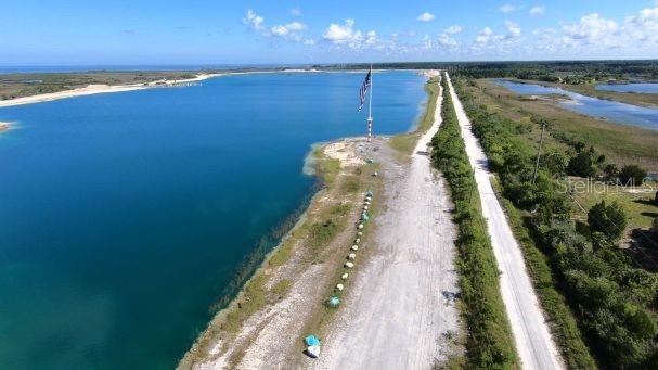 An aerial view shows a large blue lake next to a dirt road and a flagpole — 00 OLD DIXIE HIGHWAY, HUDSON, FL
