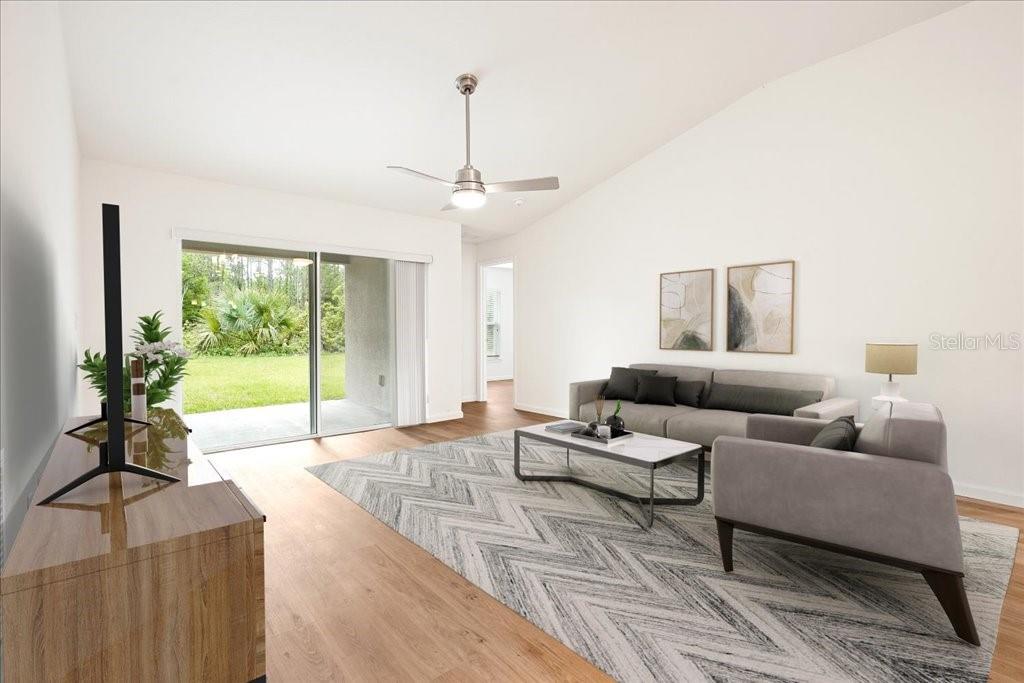 A living room features light wood flooring, a gray sofa, a patterned rug, and sliding doors — 23 WHITTINGTON DRIVE, PALM COAST, FL