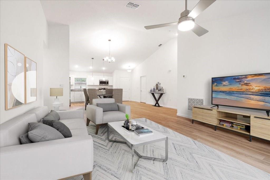 A living room with a sofa, armchair, coffee table, and television, opening into a kitchen — 23 WHITTINGTON DRIVE, PALM COAST, FL