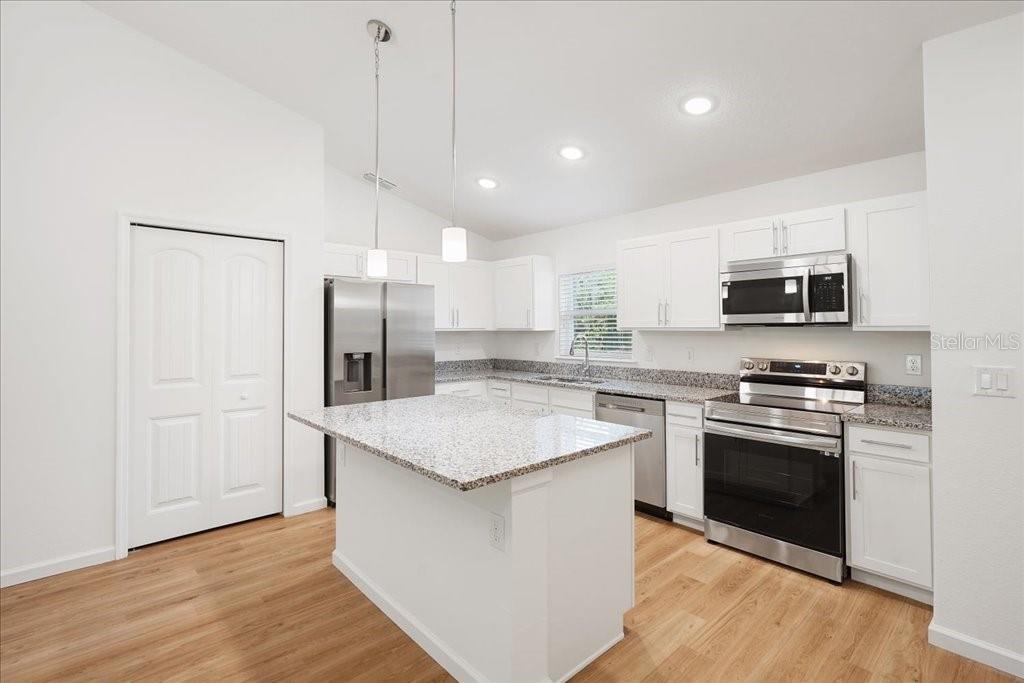 A kitchen features white cabinets, granite countertops, stainless steel appliances, and a central island — 23 WHITTINGTON DRIVE, PALM COAST, FL