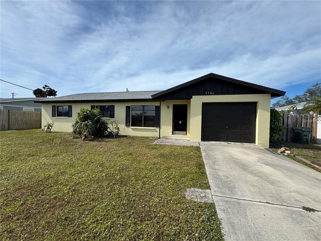 A single-story house with yellow stucco siding, a dark brown garage door, and a driveway — 1786 DAGON ROAD, VENICE, FL