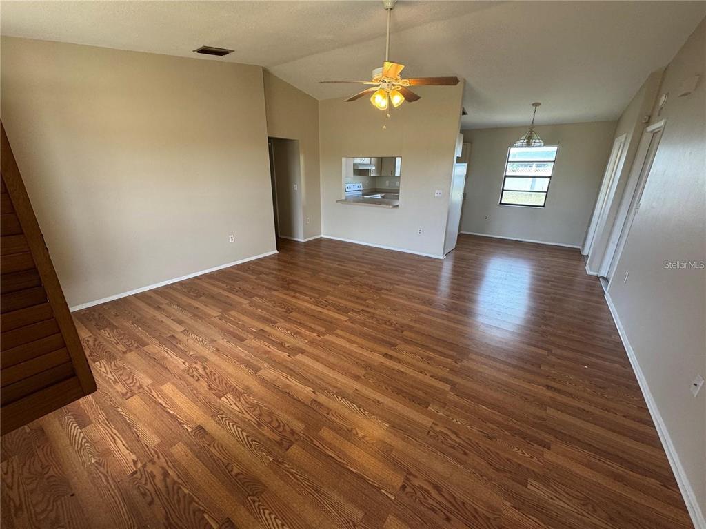 An open-concept living area features wood-look flooring, a ceiling fan, and a kitchen pass-through window — 1786 DAGON ROAD, VENICE, FL