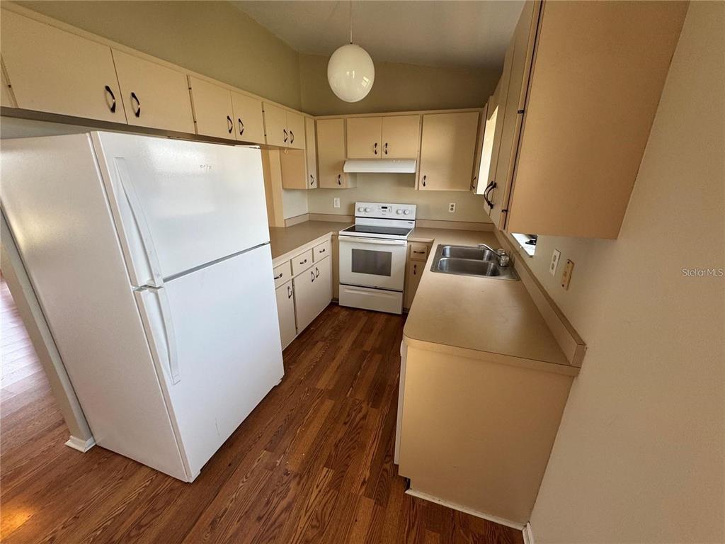 A kitchen features tan cabinets, white appliances, laminate countertops, and wood-look flooring — 1786 DAGON ROAD, VENICE, FL