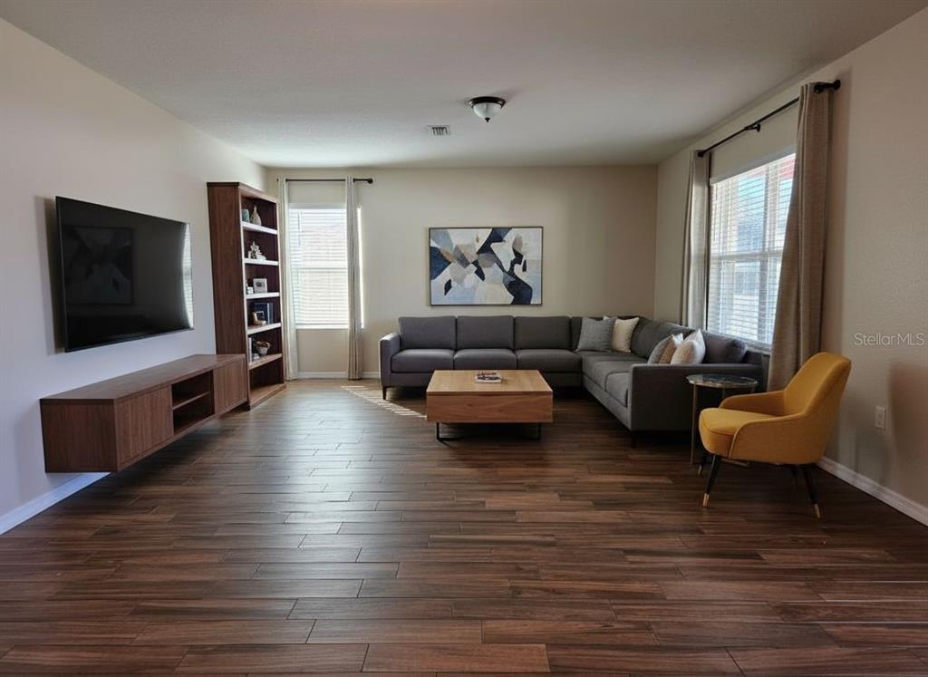 A hallway with wood-look tile flooring leads to a dining area with sliding glass doors — 109 TIERRA VERDE WAY, BRADENTON, FL
