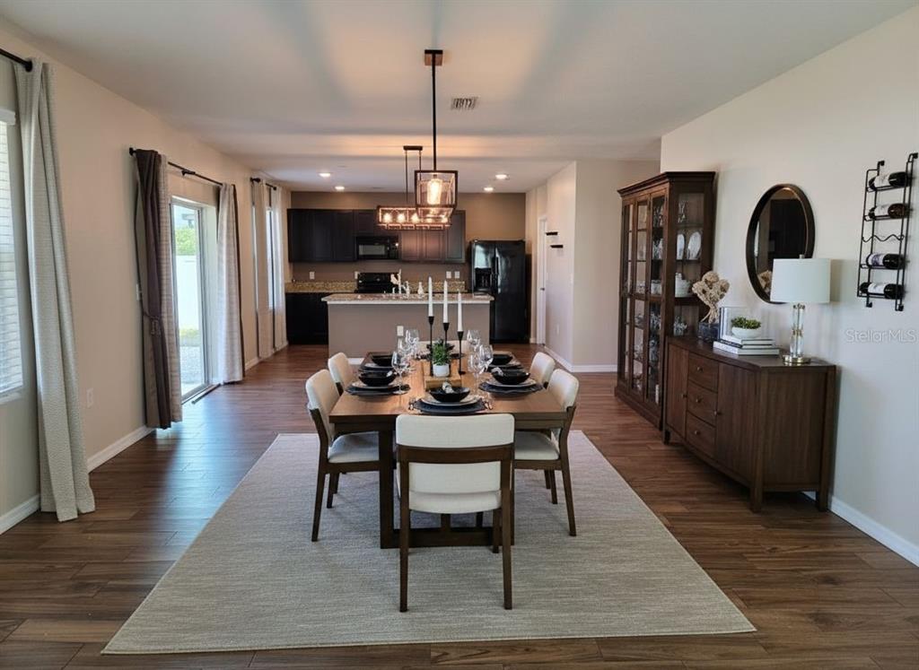 A dining room features dark wood-look flooring, a pendant light, and a window with blinds — 109 TIERRA VERDE WAY, BRADENTON, FL