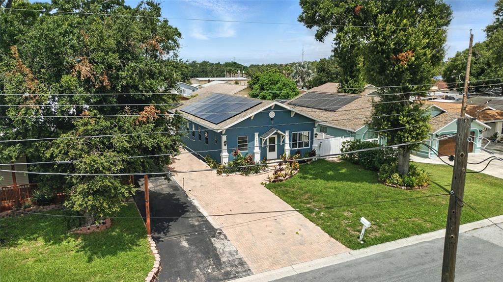 An elevated view of a blue house with solar panels and a paved driveway — 7012 N HUBERT AVENUE, TAMPA, FL