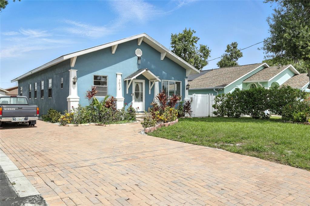 A blue house with a brick driveway and a parked pickup truck in the front yard — 7012 N HUBERT AVENUE, TAMPA, FL