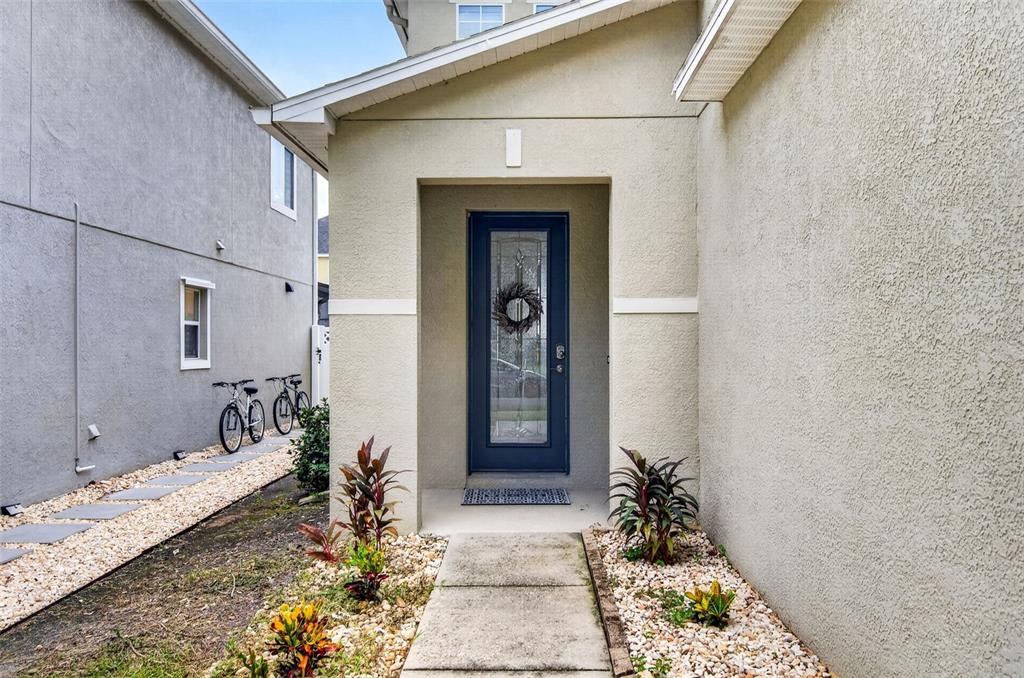 The exterior view shows a beige stucco house entrance with a dark blue front door — 7046 PENTA PLACE, WESLEY CHAPEL, FL