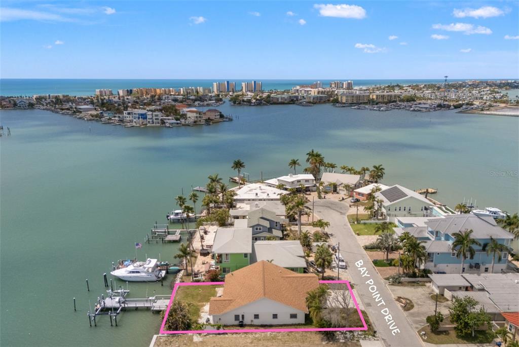 An aerial view shows a waterfront house with a private dock on a bay — 811 BAY POINT DRIVE, MADEIRA BEACH, FL
