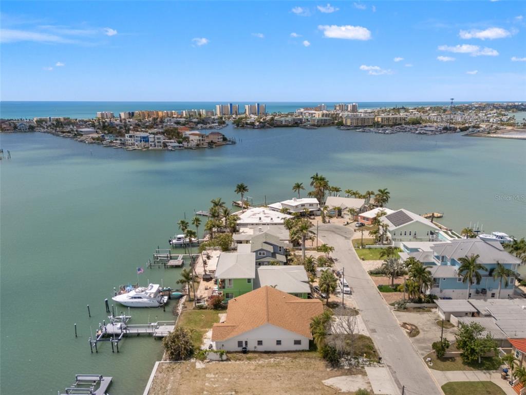 An aerial view shows waterfront homes with private docks along a bay under a blue sky — 811 BAY POINT DRIVE, MADEIRA BEACH, FL