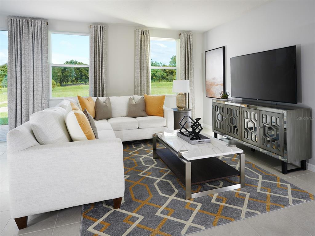 A living room features a white sectional sofa, a patterned rug, and a mirrored media console — 4539 RANGELAND WAY, ST CLOUD, FL