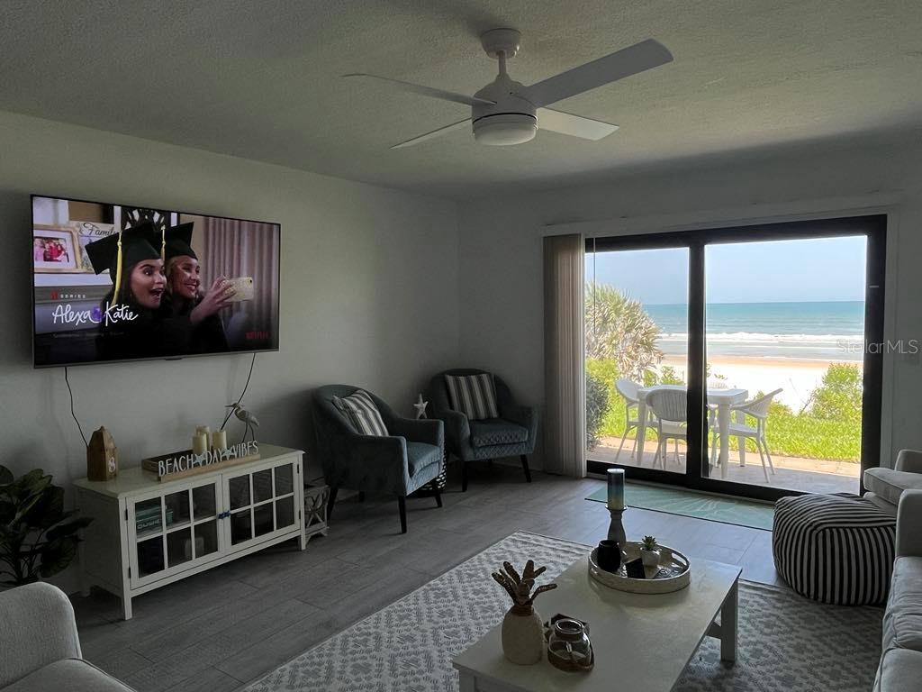 A living room features a television, two armchairs, and a sliding door overlooking the beach — 8550 A1A #261 S UNIT 25161, ST AUGUSTINE, FL