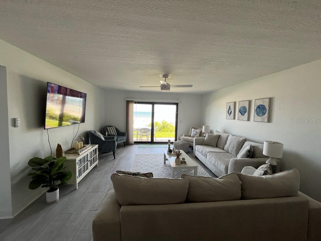 A living room with light wood-look flooring, a large sectional sofa, and a beach view — 8550 A1A #261 S UNIT 25161, ST AUGUSTINE, FL