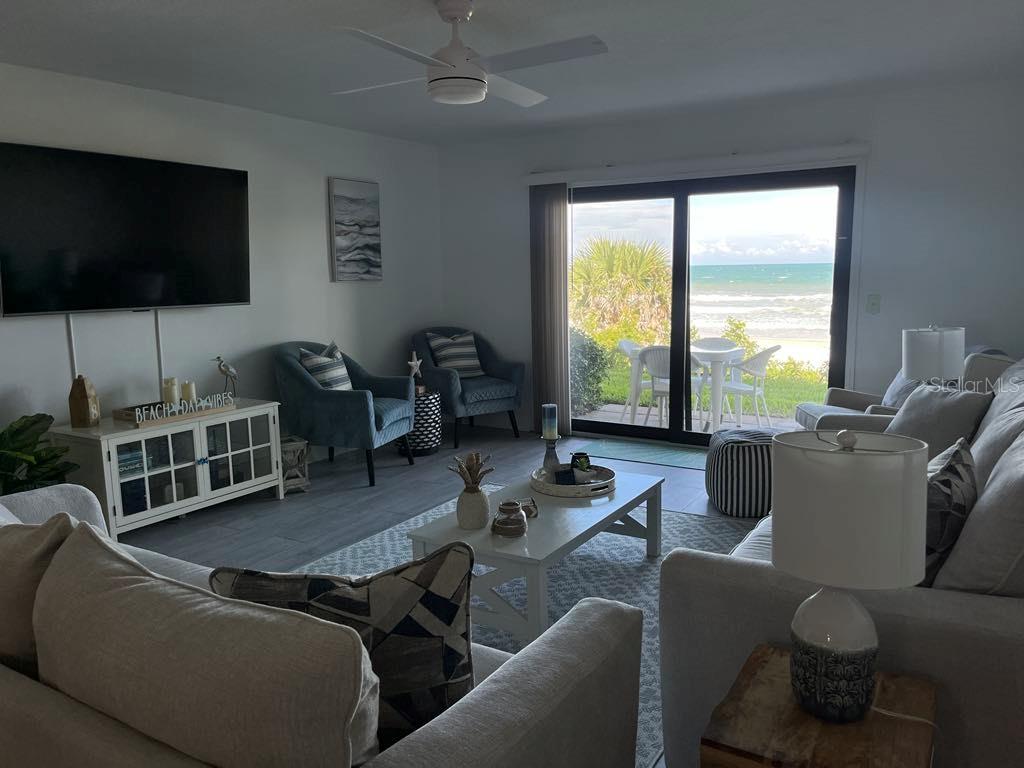 A living room features a television, seating, a coffee table, and sliding doors overlooking the ocean — 8550 A1A #261 S UNIT 25161, ST AUGUSTINE, FL