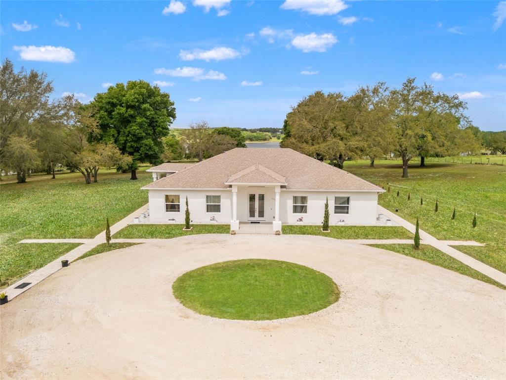 An aerial view of a white single-story house with a circular gravel driveway and lawn — 11155 CHERRY LAKE ROAD, CLERMONT, FL