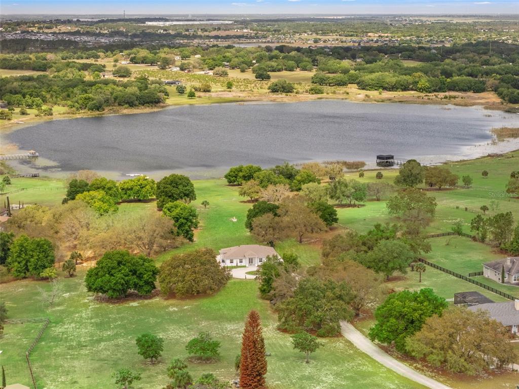An aerial view shows a single-story house situated on a large, grassy lot by a lake — 11155 CHERRY LAKE ROAD, CLERMONT, FL