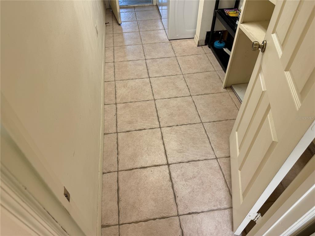 A laundry room features beige square floor tiles and a white door leading outside — 8451 SW 14TH LANE, OKEECHOBEE, FL