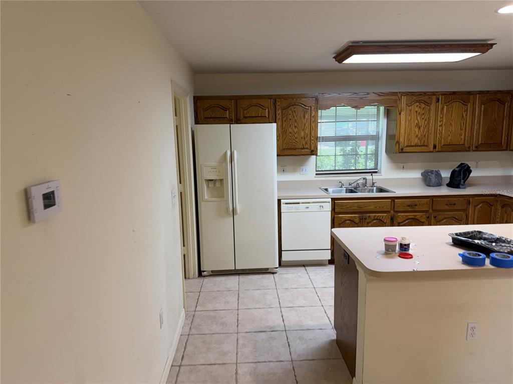 A kitchen with white appliances, oak cabinets, a tiled floor, and a kitchen island — 8451 SW 14TH LANE, OKEECHOBEE, FL