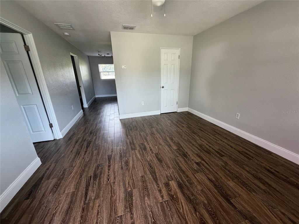An empty room features dark wood-look flooring, light gray walls, and white trim — 502 VARSITY STREET, WINTER GARDEN, FL
