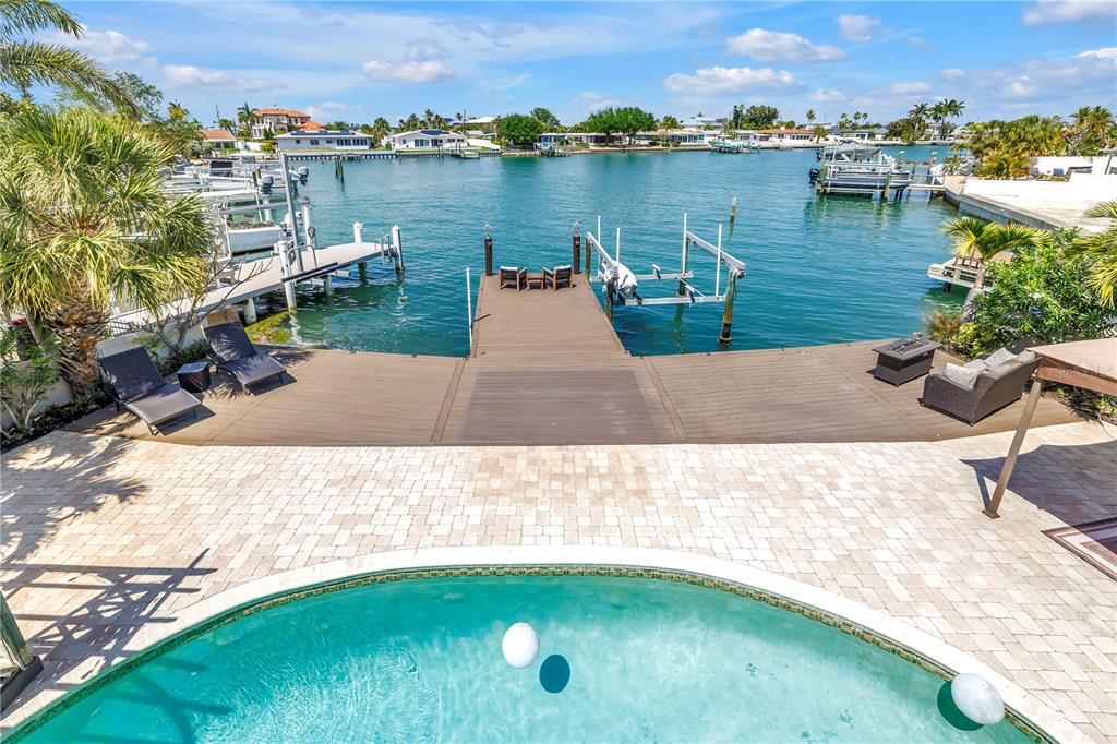A swimming pool overlooks a wooden deck and boat dock on a canal — 3945 POINSETTIA DRIVE, ST PETE BEACH, FL