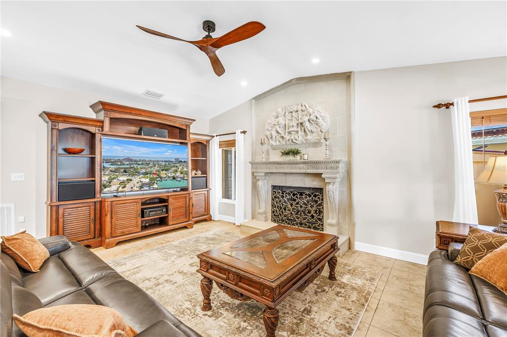 A living room features a large entertainment center, a stone fireplace, and two leather sofas — 3945 POINSETTIA DRIVE, ST PETE BEACH, FL