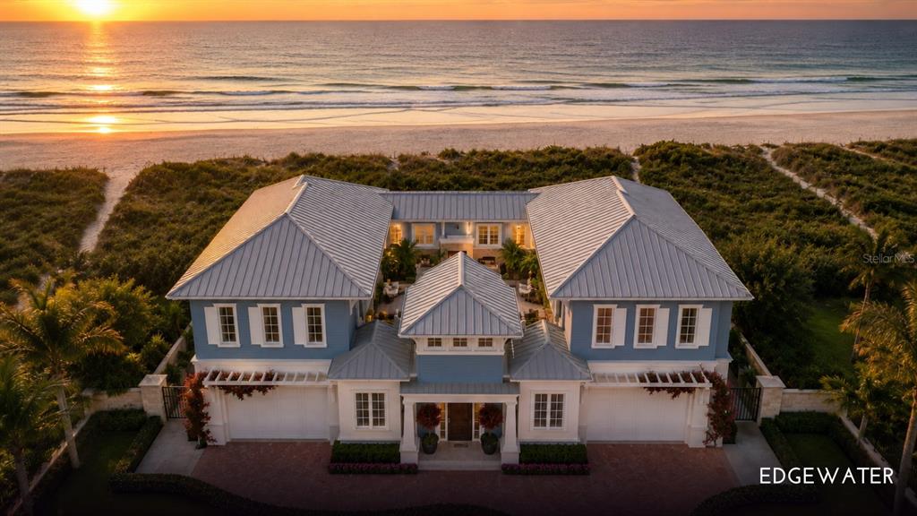 An aerial view of a blue two-story beachfront house with a metal roof at sunset — 1420/1440 GULF BOULEVARD, BELLEAIR SHORE, FL