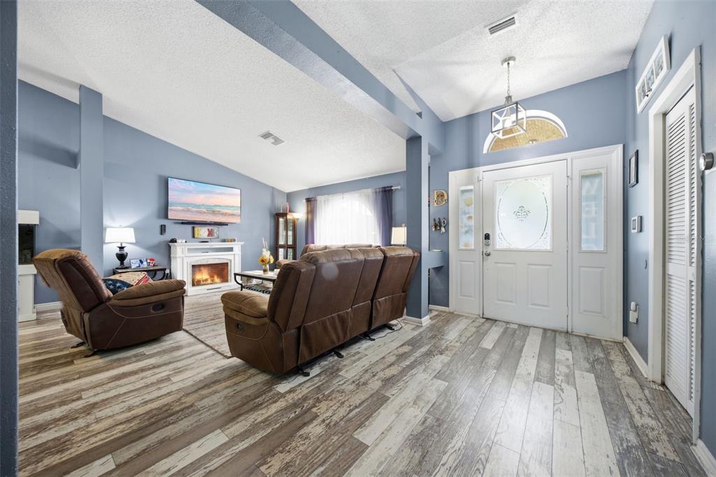 A living room with wood-look flooring, a fireplace, and a front entryway with a white door — 13801 WHITBY ROAD, HUDSON, FL