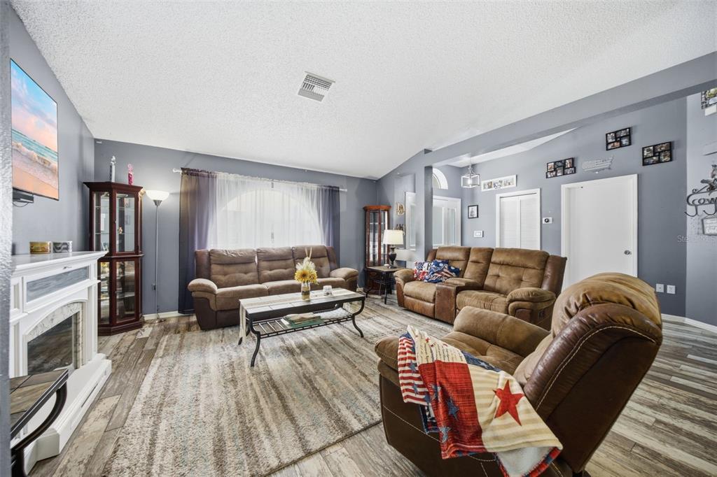 A living room features brown leather furniture, a fireplace, and wood-look tile flooring — 13801 WHITBY ROAD, HUDSON, FL