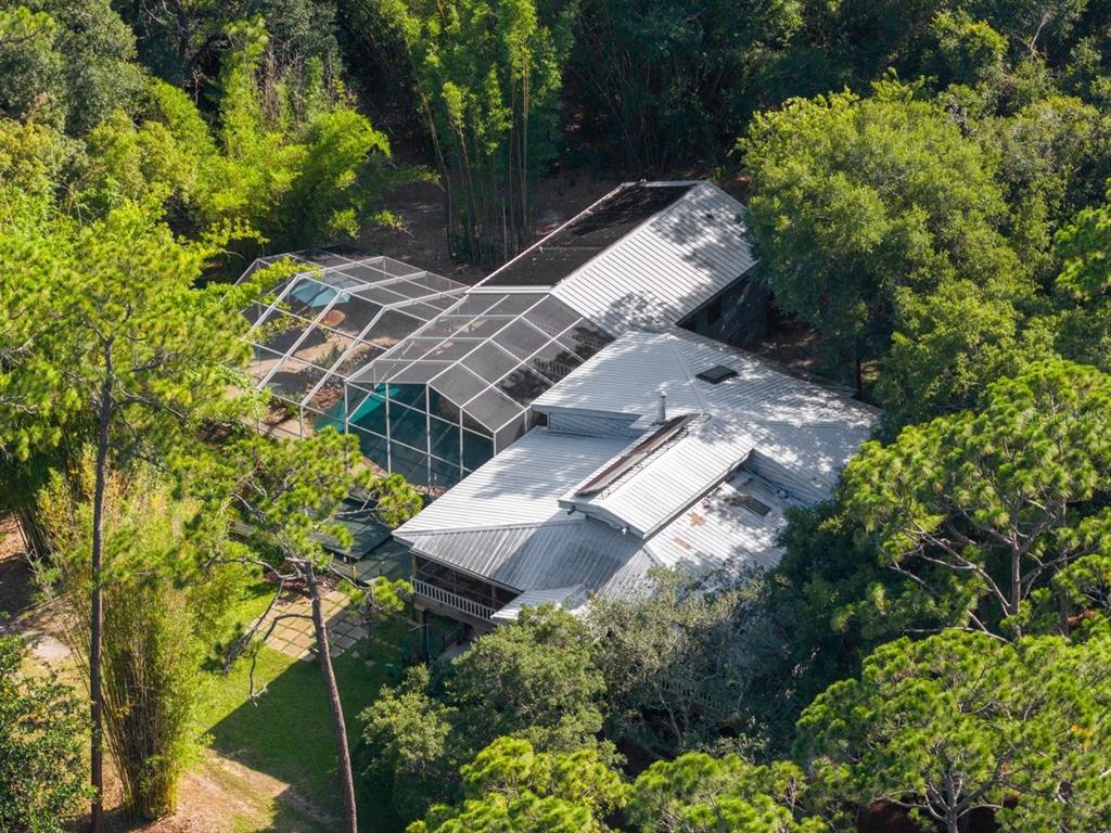 An aerial view of a house with a metal roof and a screened-in pool enclosure — 400 PINE BLUFF TRAIL, ORMOND BEACH, FL