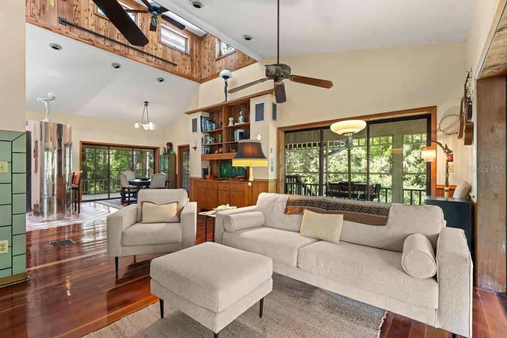 A living room features a vaulted wood-paneled ceiling, hardwood floors, and large sliding glass doors — 400 PINE BLUFF TRAIL, ORMOND BEACH, FL