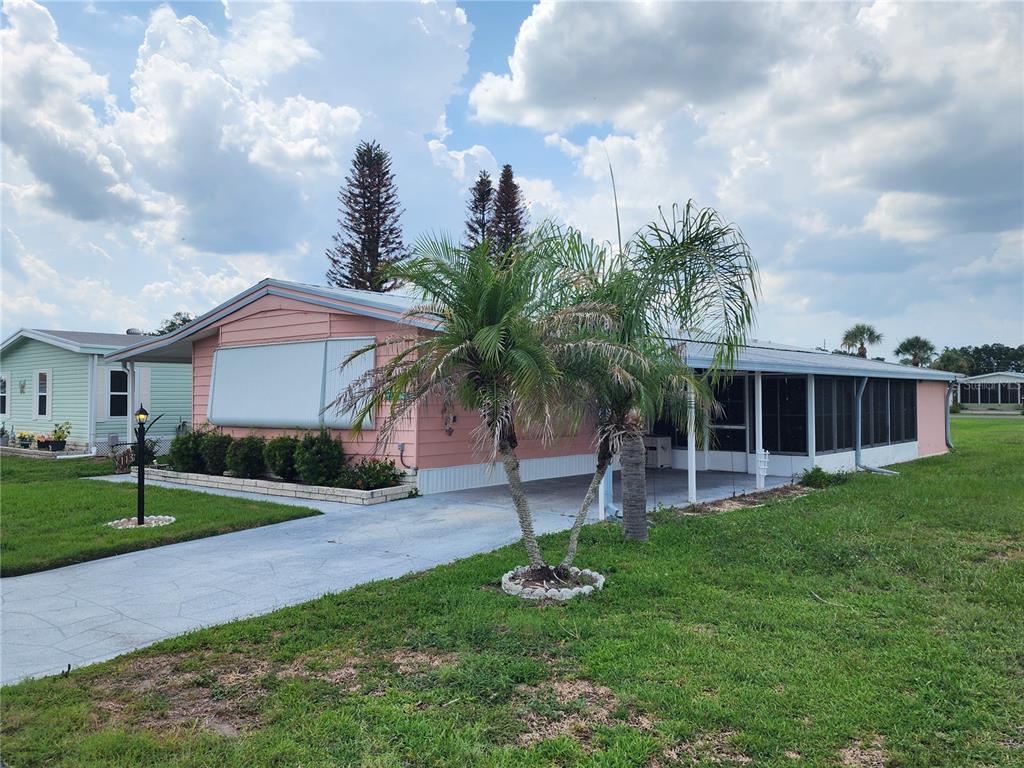 A pink mobile home with a screened-in porch and a palm tree in the front yard — 113 LAKE HAZEL DRIVE, WINTER HAVEN, FL