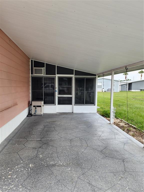 A covered concrete patio with a patterned finish sits beside a screened-in porch area — 113 LAKE HAZEL DRIVE, WINTER HAVEN, FL