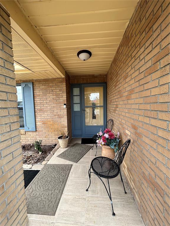 A covered brick porch features a blue front door, two metal chairs, and floor mats — 1448 E NORMANDY, DELTONA, FL