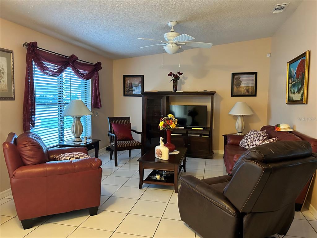 A living room features tile floors, a ceiling fan, leather furniture, and a media console — 1448 E NORMANDY, DELTONA, FL