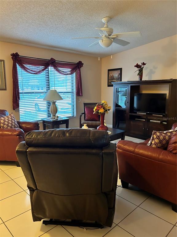 A living room features tile flooring, a ceiling fan, and leather furniture — 1448 E NORMANDY, DELTONA, FL