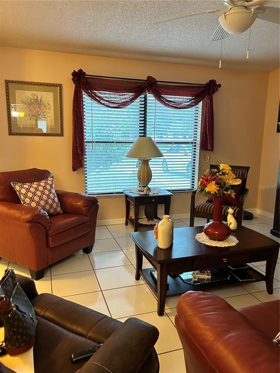 A living room features a red leather armchair, a coffee table, and a window with drapes — 1448 E NORMANDY, DELTONA, FL