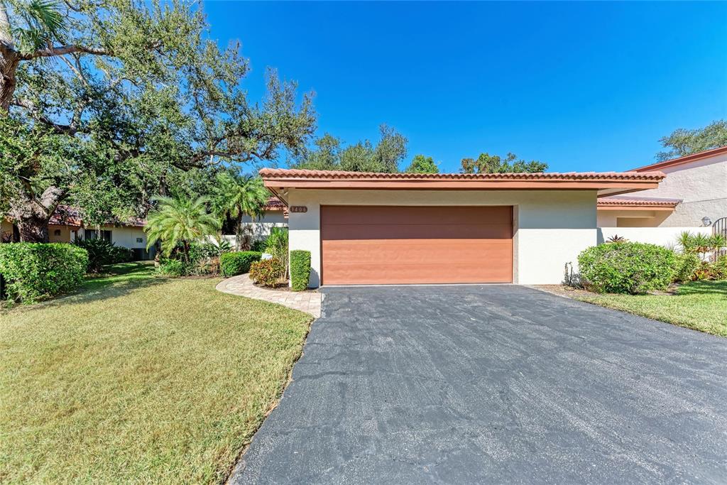 A single-story house exterior features a two-car garage, a paved driveway, and landscaped lawn — 3406 FALCON PLACE, BRADENTON, FL