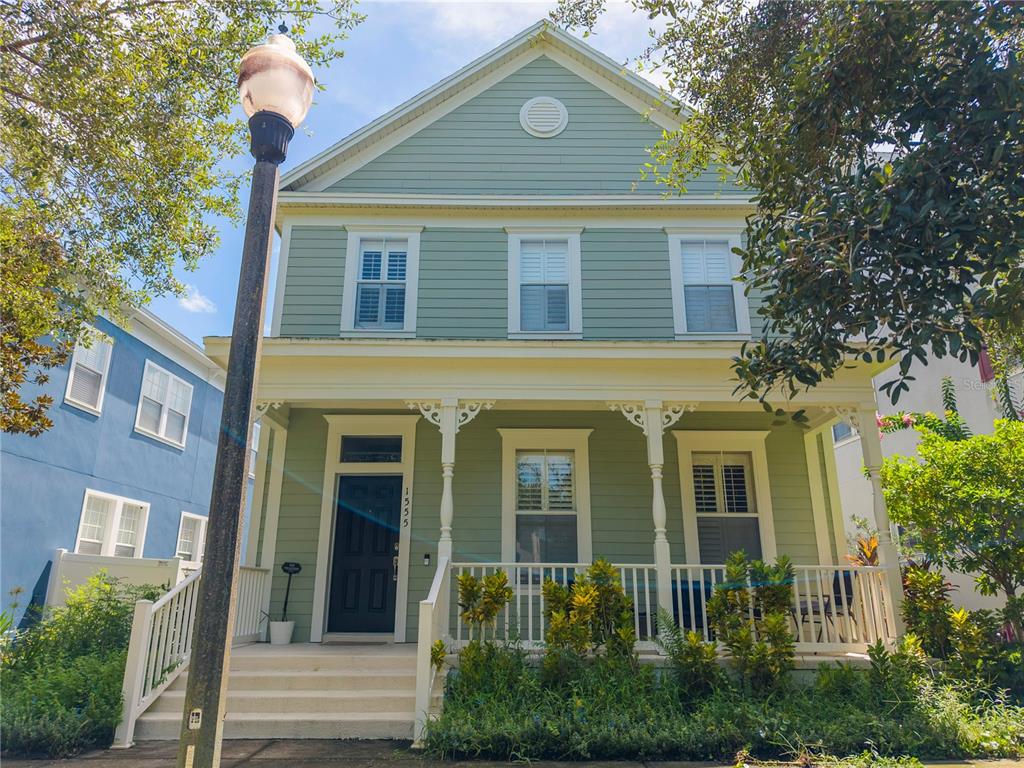 A two-story light green house with a front porch, white railings, and a black door — 1555 HANKS AVENUE, ORLANDO, FL