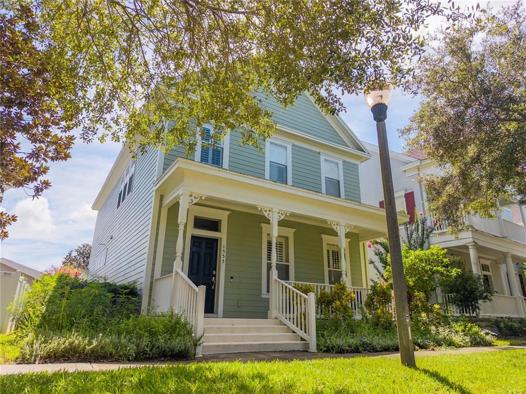 A two-story light green house with a front porch and white railings sits on a lawn — 1555 HANKS AVENUE, ORLANDO, FL