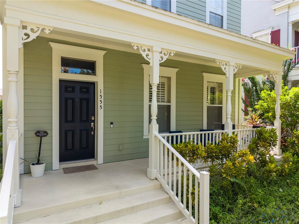 A green house exterior features a dark front door, a covered porch, and white railings — 1555 HANKS AVENUE, ORLANDO, FL