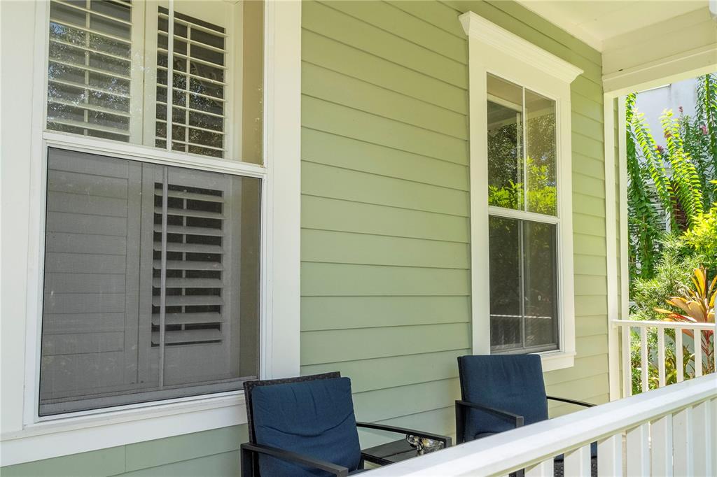 A light green house exterior features a white-railed porch with two dark blue patio chairs — 1555 HANKS AVENUE, ORLANDO, FL