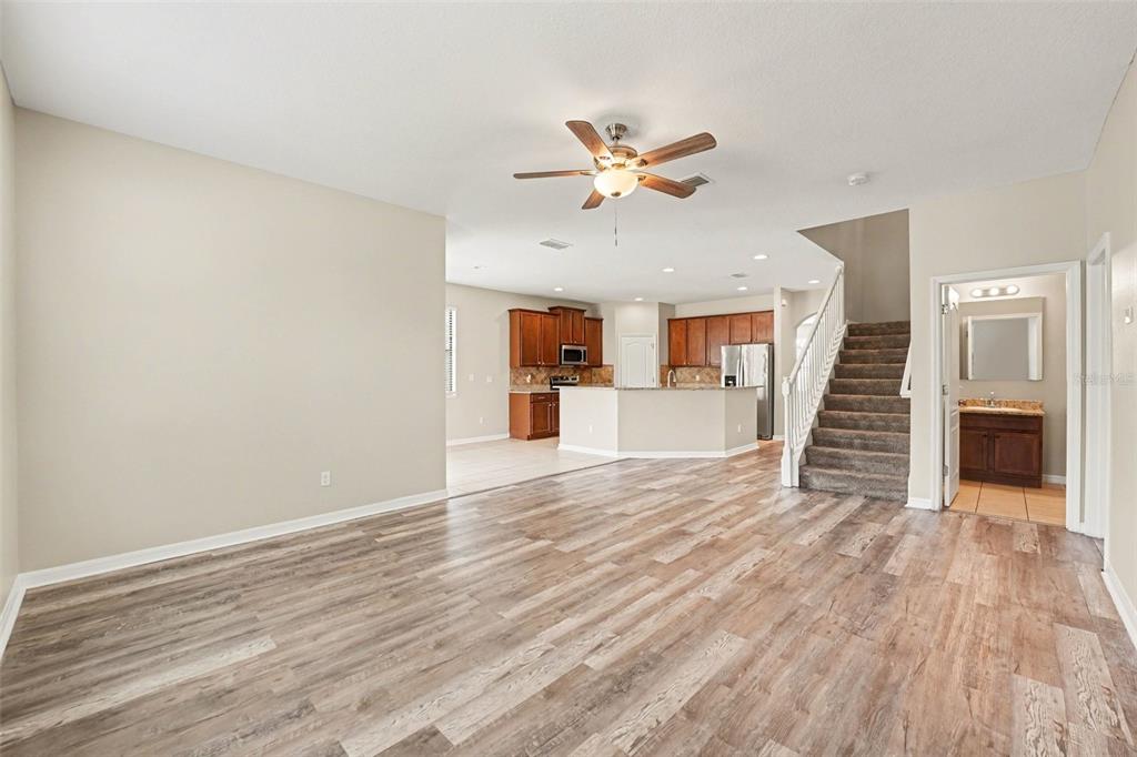 A kitchen with wood cabinets, granite countertops, and tile flooring overlooks a living area — 2727 EAGLE CLIFF DRIVE, KISSIMMEE, FL